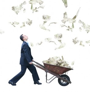 Businessman pushes wheelbarrow of money